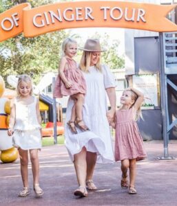 A woman and her children standing in front of the Sunshine Coast sightseeing tour sign.
