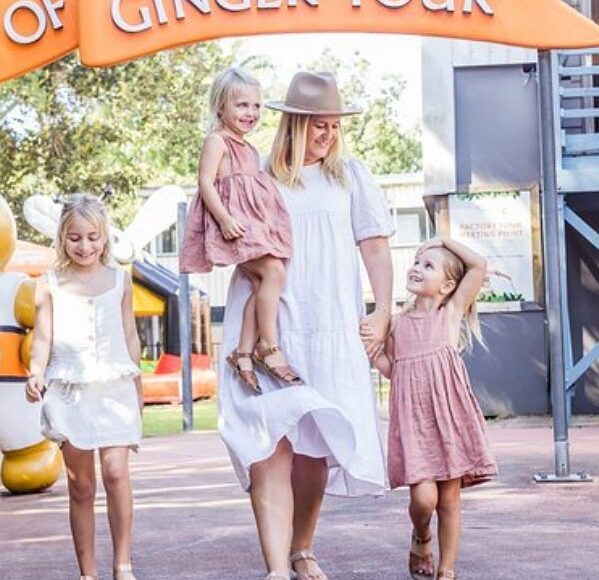 A woman and her children standing in front of the Sunshine Coast sightseeing tour sign.