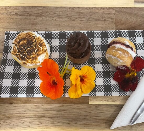 A tray of pastries and flowers on a wooden table, perfect for a sunshine coast sightseeing trip.