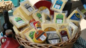A wicker basket filled with a variety of cheeses, perfect for a picnic during your Sunshine Coast day trip.