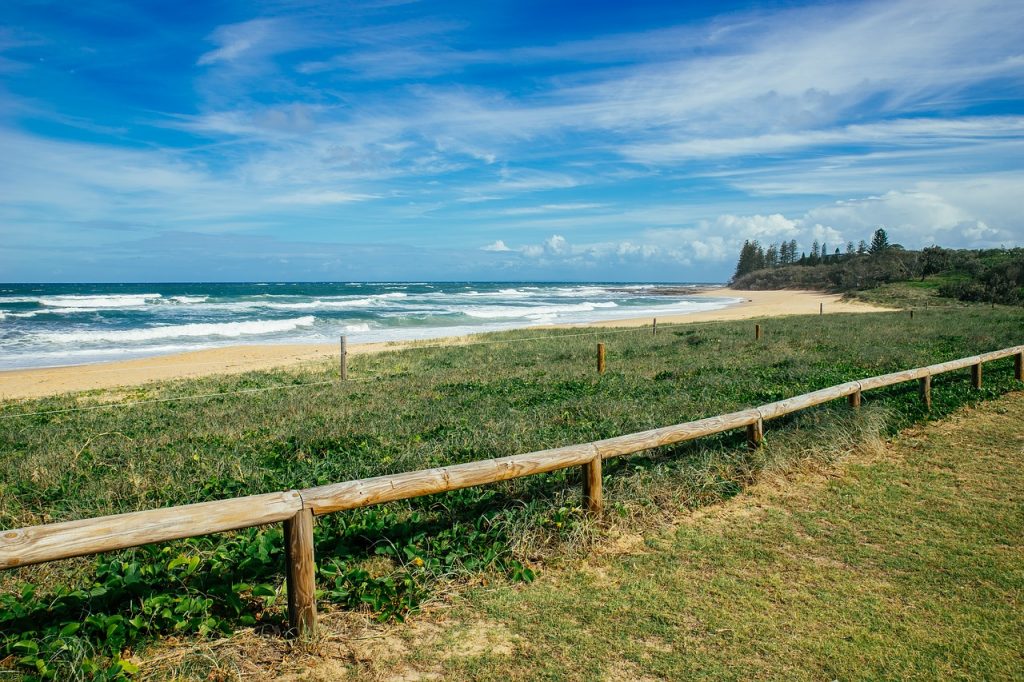 A beach with a wooden fence and ocean in the background offering a scenic view for sunshine coast sightseeing.