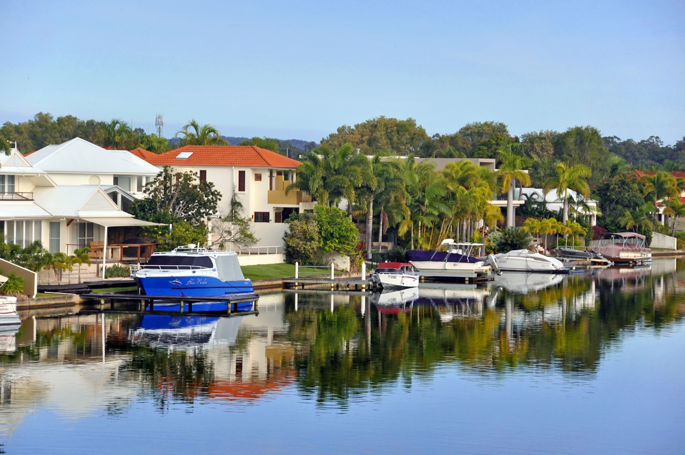 A boat docked in a waterway with houses in the background, perfect for Sunshine Coast sightseeing.