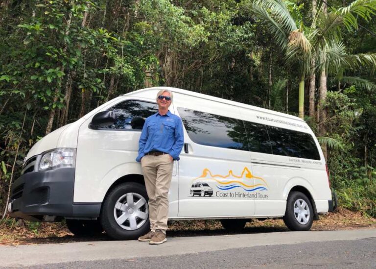 A man standing next to a white van in the forest, possibly on a Sunshine Coast tour.