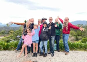 A group of people posing for a picture in front of a mountain during a sunshine coast day trip.