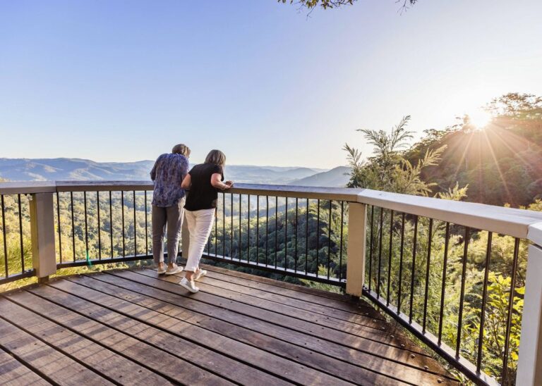 Two people admiring the view from a scenic overlook at sunset during their Montville Day Tour. Sunshine Coast Hinterland Highlights Tour: Discover Maleny and Montville